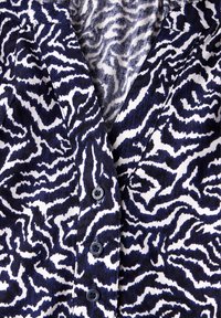 Hemd mit Knopfleiste in einem dunkelblauen und weißen Zebra-Streifen-Muster, aus einem weichen Stoff gefertigt, mit einem Schalkragen und dunklen Knöpfen entlang der Knopfleiste.