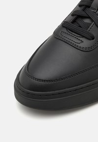 Baskets en cuir noir avec bout arrondi, surface texturée, design à lacets et semelle en caoutchouc épaisse avec de subtils détails de couture.
