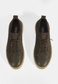 Bruine leren sneakers met ronde neuzen, contrasterende veters en subtiele stiksels. Voorzien van een lichtgewicht beige rubberen zool.