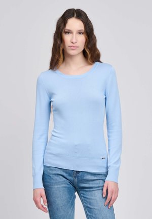 Hellblauer Pullover mit langen Ärmeln aus glattem Stoff, mit rundem Ausschnitt und gerippten Bündchen, kombiniert mit blauen Jeans aus Denim.