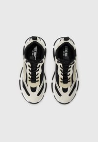 White and black sneakers featuring mesh panels, chunky soles, and contrast stitching. Includes black laces and a branded insole.