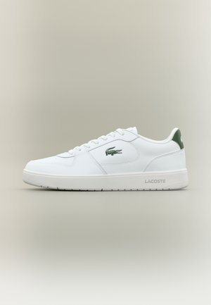 Witte leren sneaker met een gladde afwerking, groene accenten op de hak en een groen logo aan de zijkant. Beschikt over een platte zool en een ronde neus.