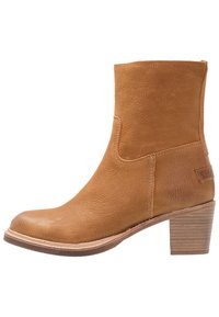 Botines de cuero marrón claro con un acabado texturizado, punta redondeada y tacón apilado. Presentan costuras mínimas y una etiqueta lateral.