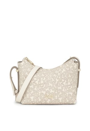 Bolso de hombro beige con un diseño curvado, que presenta un cierre de cremallera en tono dorado y una correa ajustable. Logo de la marca embellecido en la parte frontal.