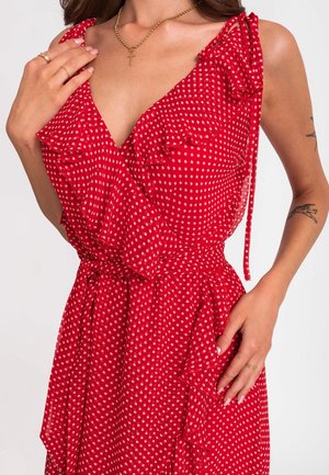 Abito rosso a pois bianchi con dettagli arricciati, scollatura a V e cintura in vita; realizzato in tessuto leggero, presenta un design fluido e una texture morbida.