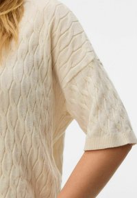 Gebreide korte mouwen trui in licht beige met een textuur van een diamantpatroon, voorzien van een ronde halslijn en een geribbelde zoom.