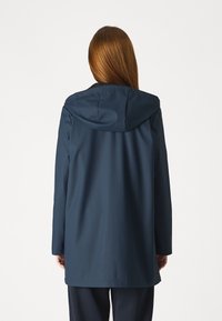 Marinblå vattentät jacka med huva, med en avslappnad passform, slät textur och långa ärmar, sedd bakifrån.