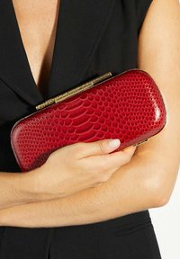Red embossed leather clutch with a textured snake pattern, featuring a gold-tone metal clasp and sleek, rectangular shape.