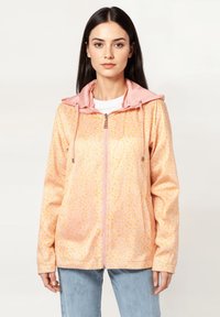 Chaqueta rosa con cremallera y capucha, con un patrón de puntos. Hecha de una tela suave, cuenta con cordones y un corte relajado.
