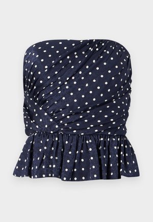 Τοπ σε ναυτικό μπλε χωρίς τιράντες με λευκές πουά, με στρατηγμένη ύφανση και βολάν στο τελείωμα στη μέση.