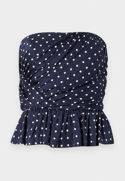 Τοπ σε ναυτικό μπλε χωρίς τιράντες με λευκές πουά, με στρατηγμένη ύφανση και βολάν στο τελείωμα στη μέση.