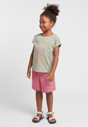 Lichtgroene katoenen T-shirt met een grafisch ontwerp en de tekst "Laten we een pauze nemen", gecombineerd met roze shorts en meerkleurige sandalen.
