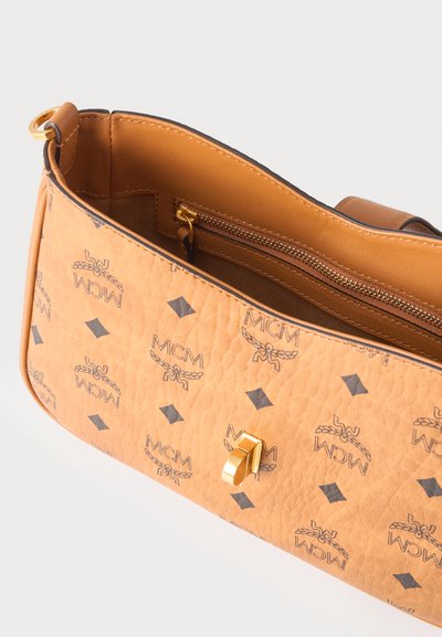 Sac à épaule MCM en cuir marron clair avec motif logo répété, fermoir doré et poche intérieure zippée, présenté ouvert vu de dessus.