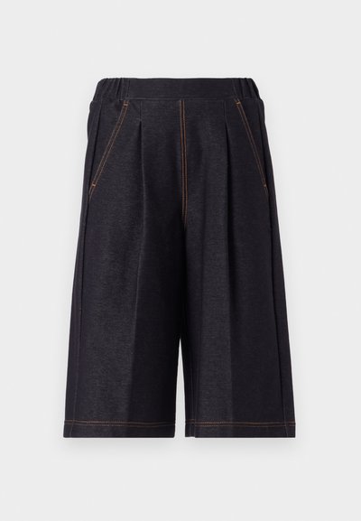 Tummanharmaat shortsit, jotka on valmistettu pehmeästä kankaasta ja joissa on taitteita sekä oranssia ompelua. Mukava joustava vyötärö ja polveen saakka ulottuva malli.