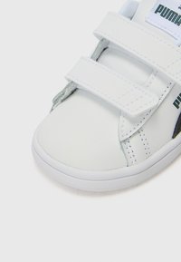 White velcro sneaker with smooth synthetic upper, rounded toe, and textured sole; features PUMA branding in green and black on the side.