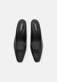 Pantofi slingback din piele neagră, cu vârf pătrat, textură netedă și branding "Calvin Klein" pe interior.