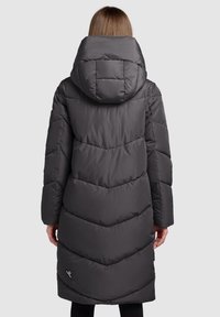 Haină lungă matlasată, de culoare gri, cu glugă, având un design matlasat în formă de V și un logo pe partea inferioară. Textură netedă și izolatoare.