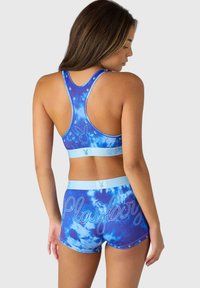 Sinine tie-dye sportlik rinnahoidja ja lühikesed püksid komplekt, millel on rhinestone aksendid ja "Playboy" logo, valmistatud venivast ja siledast kangast.