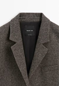 Col et revers de blazer en laine marron texturée avec doublure intérieure noire et étiquette Massimo Dutti.