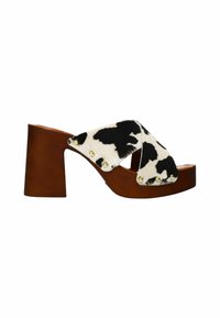 Brown wooden block-heeled sandal, featuring a cross strap in black and white cow print fabric with gold studs along the edges.
