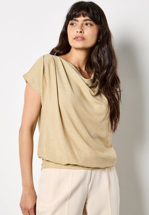 Top dorado de manga corta, elaborado con una tela suave y texturizada, que presenta un corte relajado y un drapeado suave en el escote.