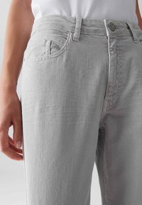 Jeans in denim grigio chiaro con vestibilità slim, caratterizzati da un classico design a cinque tasche, bottone in metallo e dettagli di cucitura sottili.