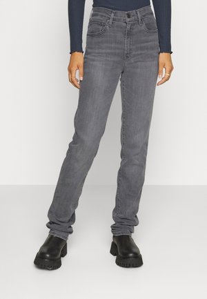 Person wearing grey straight-leg jeans and black chunky boots, standing against a plain white background.