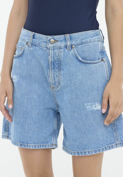 Shorts de mezclilla azul claro con dobladillo deshilachado, cinco bolsillos y detalles desgastados. Cuenta con un cierre de botón metálico y lazos para cinturón.