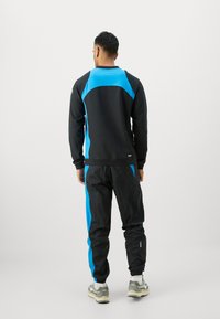 Black and blue tracksuit featuring a black sweatshirt with blue accents on shoulders and a matching pair of black pants with blue stripe.
