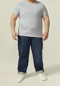 T-shirt gris à manches courtes associé à un jean denim indigo foncé, ourlé aux chevilles, et des chaussures blanches faciles à enfiler. Tenue simple et décontractée.