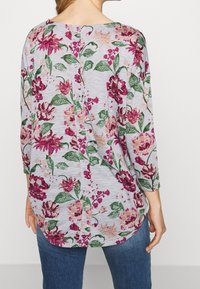 Langärmliges graues Oberteil mit Blumenmuster in Burgunderrot, Pink und Grün. Verfügt über einen runden Ausschnitt und Knopfdetails entlang des Rückens.