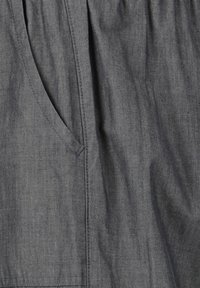 Harmaa kangas pehmeällä pinnalla, jossa on sivutasku ja huomaamaton tikkaus. Materiaali näyttää kevyeltä ja hengittävältä.