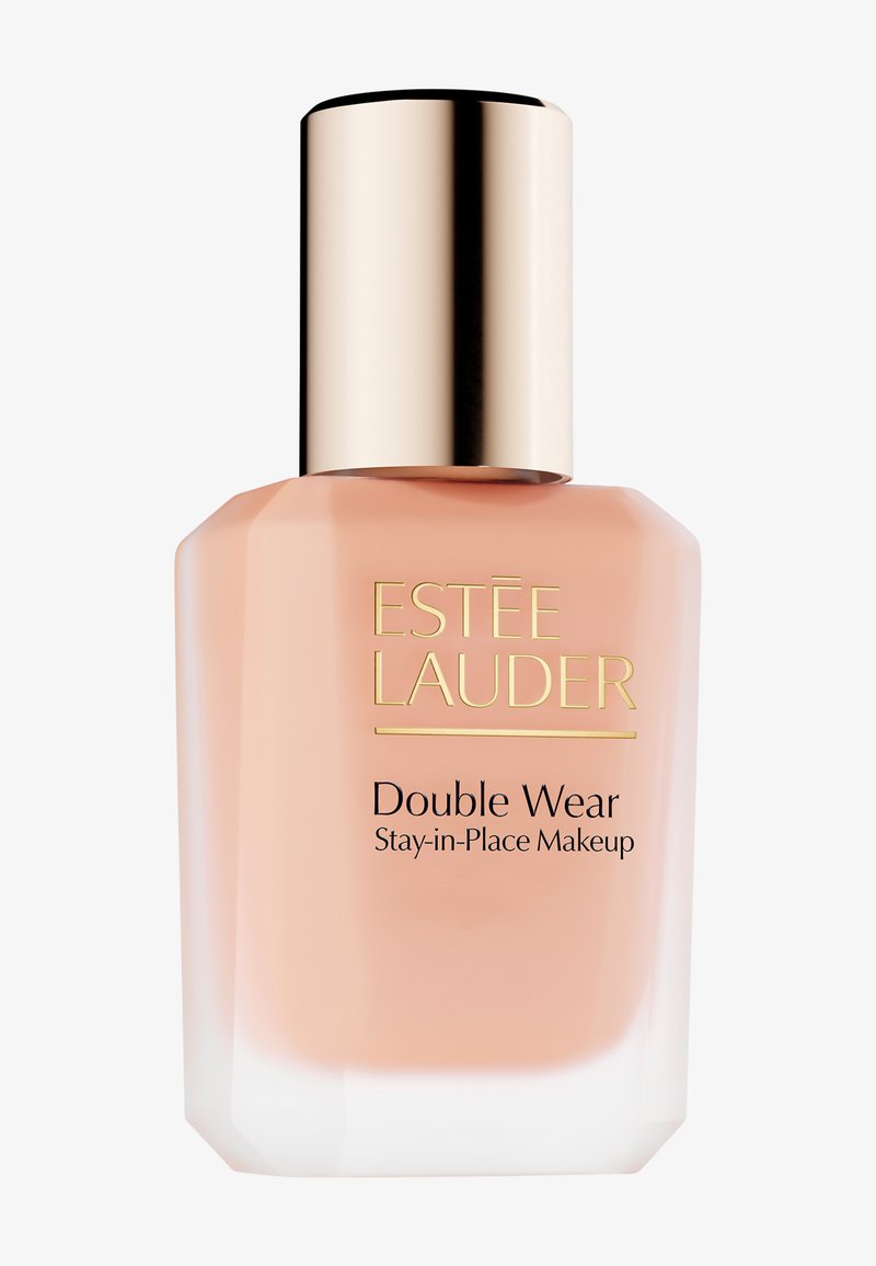 Estee Lauder Double Wear Stay-in-Place-make-up in een doorzichtige glazen fles met een roze tint en een gouden metalen dop, hoekig ontwerp.