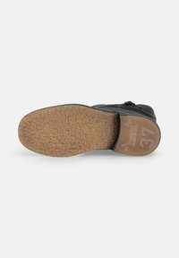 Chaussure en cuir noir avec une semelle en caoutchouc texturée. Présente un dessus lisse et la taille 37 estampillée sur le talon. La semelle affiche une finition naturelle et granulée.