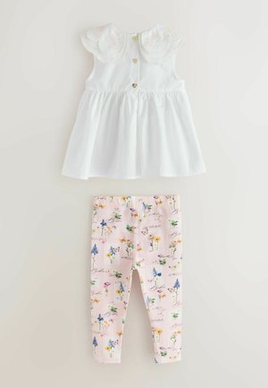 Biely detský bezrukávnik s volánovým čipkovým golierom a gombíkmi v tvare srdca v kombinácii s ružovými legínami s kvetinovým a motýľovým vzorom.