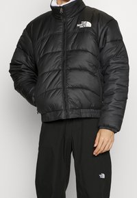 Czarna kurtka puchowa z zamkiem z przodu, prążkowanymi mankietami i dolnym brzegiem. Posiada wzory szycia oraz białe logo na klatce piersiowej. Wykonana z lekkiego materiału.
