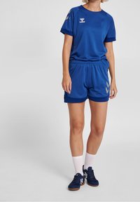 Blått idrottskläder bestående av en t-shirt med kort ärm och shorts tillverkade av andningsbart material med grå detaljer och en logotyp på bröstet och sidan.