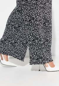 Czarno-białe wzmocnione szerokie spodnie z teksturowanej tkaniny, w połączeniu z białymi szpilkami w szpic z przezroczystym detalem po boku.