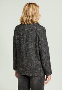 Zwart-wit visgraatpatroon jas, medium gewicht, met een enkele split aan de achterkant en lange mouwen. Ontworpen met een ontspannen pasvorm.