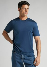 T-shirt bleu marine à manches courtes en tissu lisse et léger. Encolure ronde avec une coupe décontractée, associé à un jean en denim bleu clair.