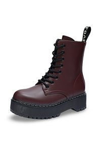 Bottines bourgogne avec lacets noirs, semelle épaisse et décorations cousues. Elles présentent une languette avec du texte blanc sur le talon.