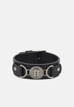 Black leather bracelet with silver lion head medallion and circular metal accents, adjustable buckle clasp.