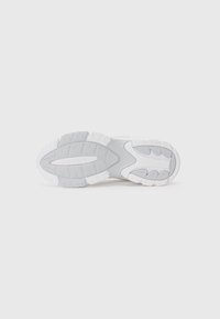 Lacoste sneakersåle i grå og hvit gummi, med et teksturert mønster og branding preget på overflaten.