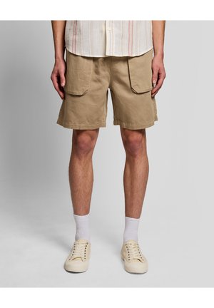 Mand iført beige cargoshorts, hvide sokker, cremefarvede lærredssneakers og en lysefarvet skjorte med knapper og lodrette striber.