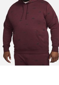 Maroon hoodie made of soft fabric with a drawstring hood. Features black Nike logos printed throughout and a front kangaroo pocket.