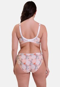 Ensemble de bikini floral avec un schéma de couleurs pêche et blanc. Le haut est doté de bretelles réglables et d'un fermoir, avec un motif floral sur l'ensemble.