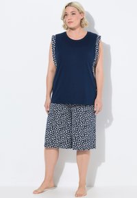 Navy blauwe mouwloze top met bloemmotief op de schouders, gecombineerd met bijpassende wijde broek met een witte bloemenprint.