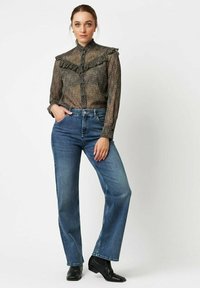 Sheer, textured black blouse with ruffled collar, paired with high-waisted, straight-leg blue jeans and black ankle boots.