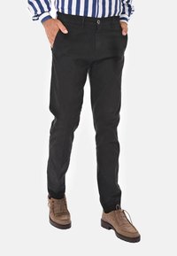 Chinos neri con vestibilità slim, realizzati in tessuto misto cotone. Presentano un classico design a cinque tasche e una superficie leggermente testurizzata.