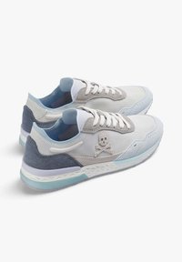 Baskets légères présentant une palette de couleurs grise et bleue, fabriquées en toile et en daim, avec un design à lacets et un logo de crâne sur le côté.